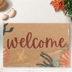 a welcome mat with shells and seashells on it next to a potted plant