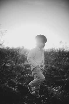 a young boy standing on top of a grass covered field