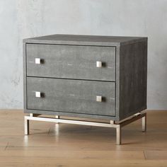 a grey chest of drawers sitting on top of a wooden floor