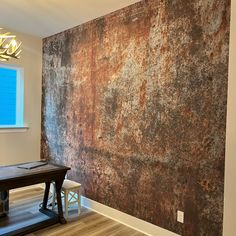 an empty room with a wooden table in front of a rusted wall