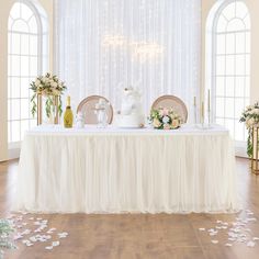 a table with flowers and candles on it in front of a white curtained wall