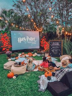 people sitting in the grass watching harry potter on a big screen at an outdoor movie theater