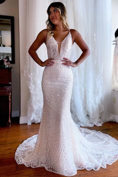 a woman standing in front of a window wearing a wedding dress with an open back