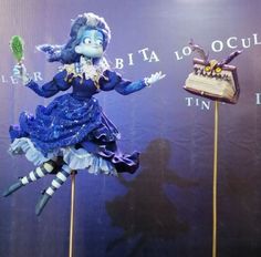 there is a blue and white doll on top of two wooden sticks with an object in the background