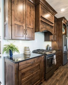 a kitchen with wooden cabinets and stainless steel appliance, wood flooring and white walls