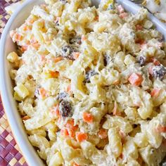 a white bowl filled with macaroni salad on top of a purple and yellow table cloth