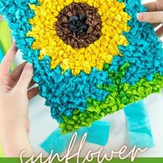 someone is holding up a crocheted sunflower pillow made with yarn and scissors