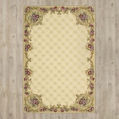 a beige rug with flowers and vines on the bottom is in front of a wooden floor