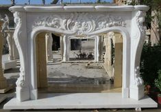 an ornate white fireplace surround in the middle of a courtyard