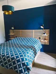 a bedroom with blue walls and wooden headboard on the bed, along with two lamps