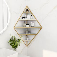 a white bathroom with gold shelving and a round mirror on the wall above it