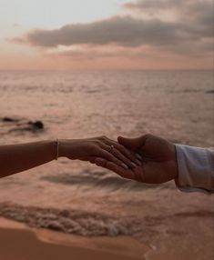 a couple holding hands on the beach at sunset