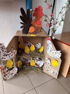 an open cardboard box filled with chickens and other farm animal crafts on top of a tiled floor