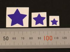 three blue stars on white stickers next to a measuring ruler with the numbers 50, 60, and 90