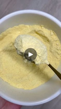 a hand holding a spoon in a white bowl filled with powdered sugar and butter