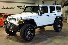 a white jeep is parked in a showroom