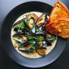 there is a plate of mussels and bread on the table