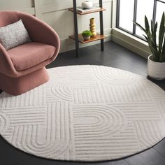 a living room area with a chair and rug on the floor next to a potted plant