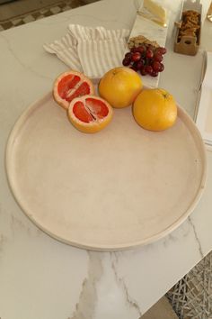 two grapefruits, oranges and grapes on a plate