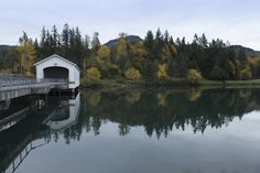 a white covered bridge over a body of water with trees in the backgroud