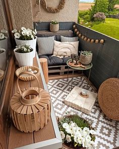 a balcony with potted plants and decorative items on the floor, along with other outdoor furniture