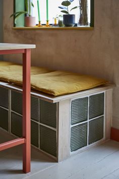 a wooden bench sitting under a window next to a table