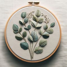 a close up of a embroidery on a white surface with green leaves and flowers in it