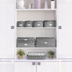 the shelves are filled with storage containers and flowers in vases on top of them