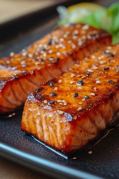 two pieces of salmon sitting on top of a black plate