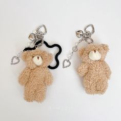 two teddy bear key chains are shown on a white surface, one is brown and the other is black