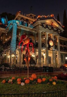 a large house decorated for halloween with pumpkins and lights