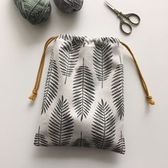 a drawstring bag sitting on top of a table next to yarn and scissors