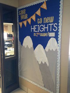 a bulletin board with mountains and bunting on the wall in front of an open door