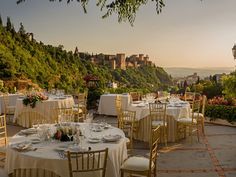 an outdoor dining area with tables and chairs set up for a formal dinner overlooking the city