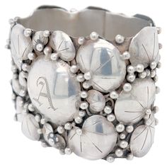 a silver bracelet with balls and beads on the outside, in front of a white background