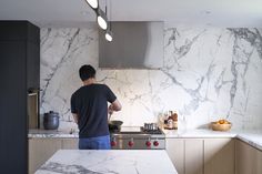 a man standing at the kitchen counter in front of a stove top oven and sink