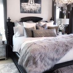 a bedroom with a bed, chandelier and pillows on it's headboard