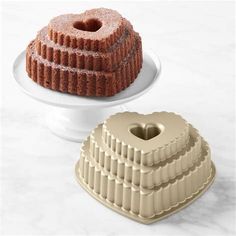 two bundt cakes sitting on top of a white cake plate next to each other