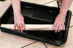 a person with their hands on a piece of paper in a black box that is sitting on the floor