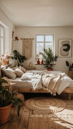 a bed sitting on top of a wooden floor next to two potted plants in front of a window