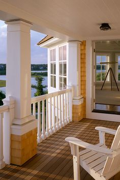 a white chair sitting on top of a wooden porch next to a door and windows