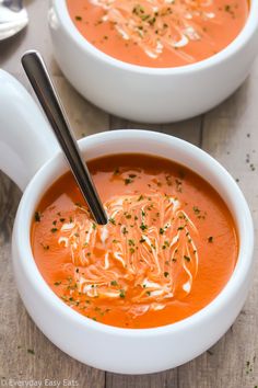 two bowls of tomato soup on a wooden table