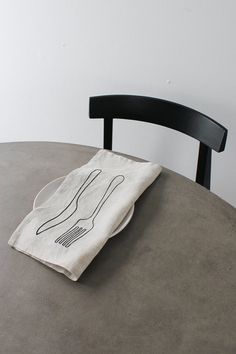 a white towel sitting on top of a wooden table next to a black dining chair