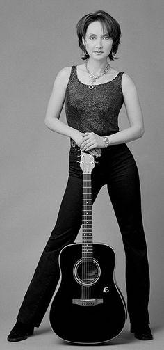 a woman posing with an acoustic guitar