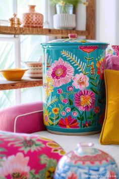 a brightly colored canister sitting on top of a table next to pillows and other decorative items