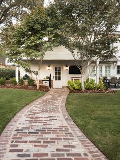 a brick walkway leading to a white house