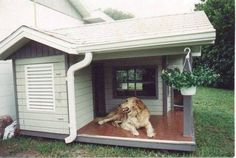 a dog house with a large brown dog sitting in it's door and porch