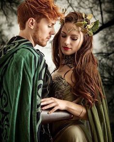 a man and woman dressed up in medieval costumes looking at each other's foreheads