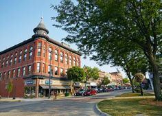 an old red brick building on the corner of a street with cars parked in front