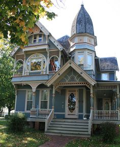 an old victorian style house with blue siding and white trim on the front porch is shown